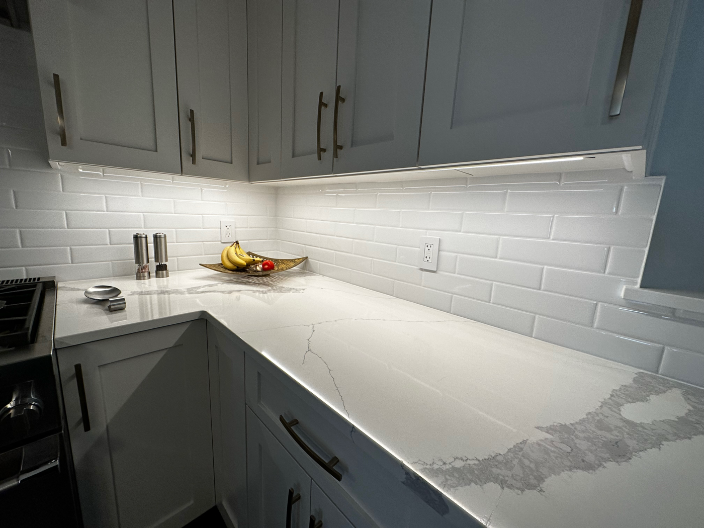 Under-cabinet LED lighting and white subway tile in a designer kitchen
