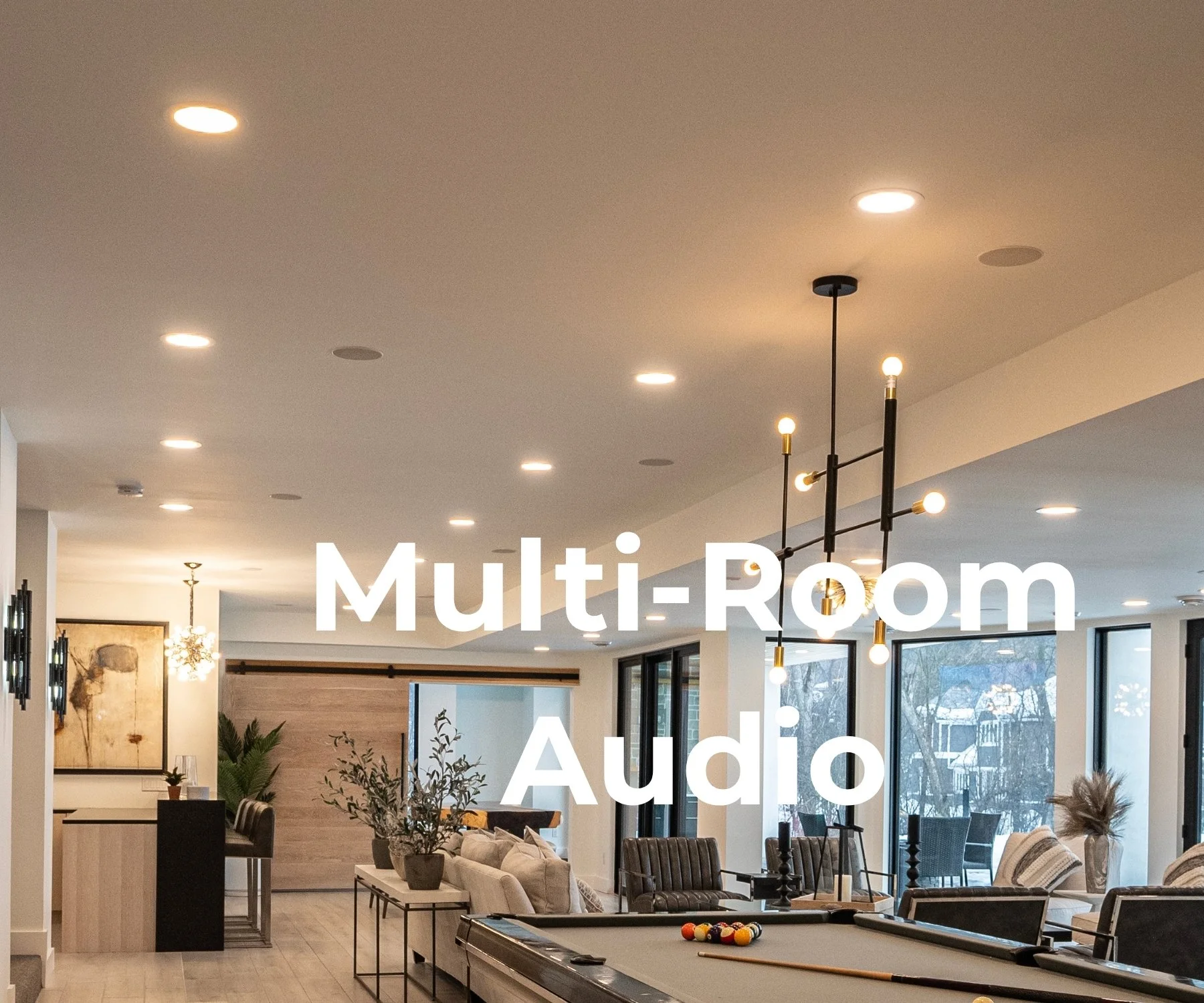 Open-plan living room with in-ceiling speakers, sectional seating, and a billiards table for whole-home audio